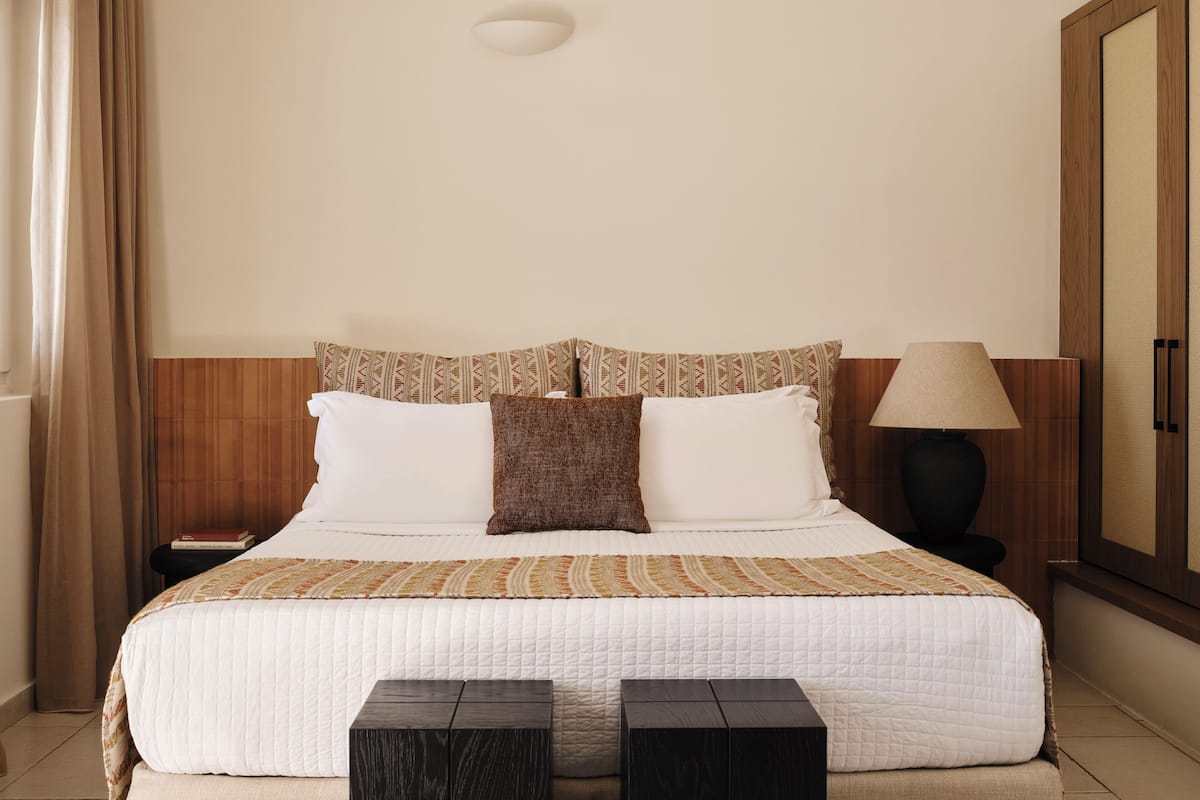 Une chambre d’hôtel avec un lit, une table de chevet, une lampe et une armoire.