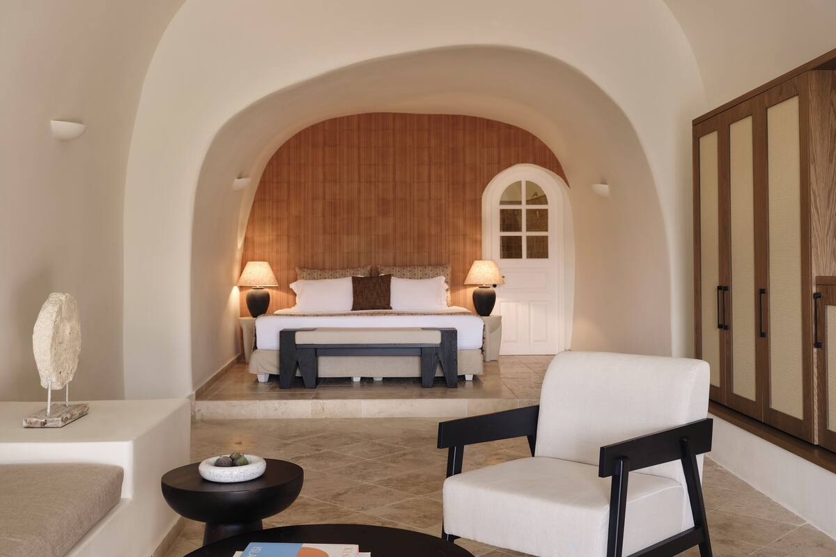 Un dormitorio moderno con una cama grande, dos lámparas de noche, un cabecero de madera y una puerta blanca.