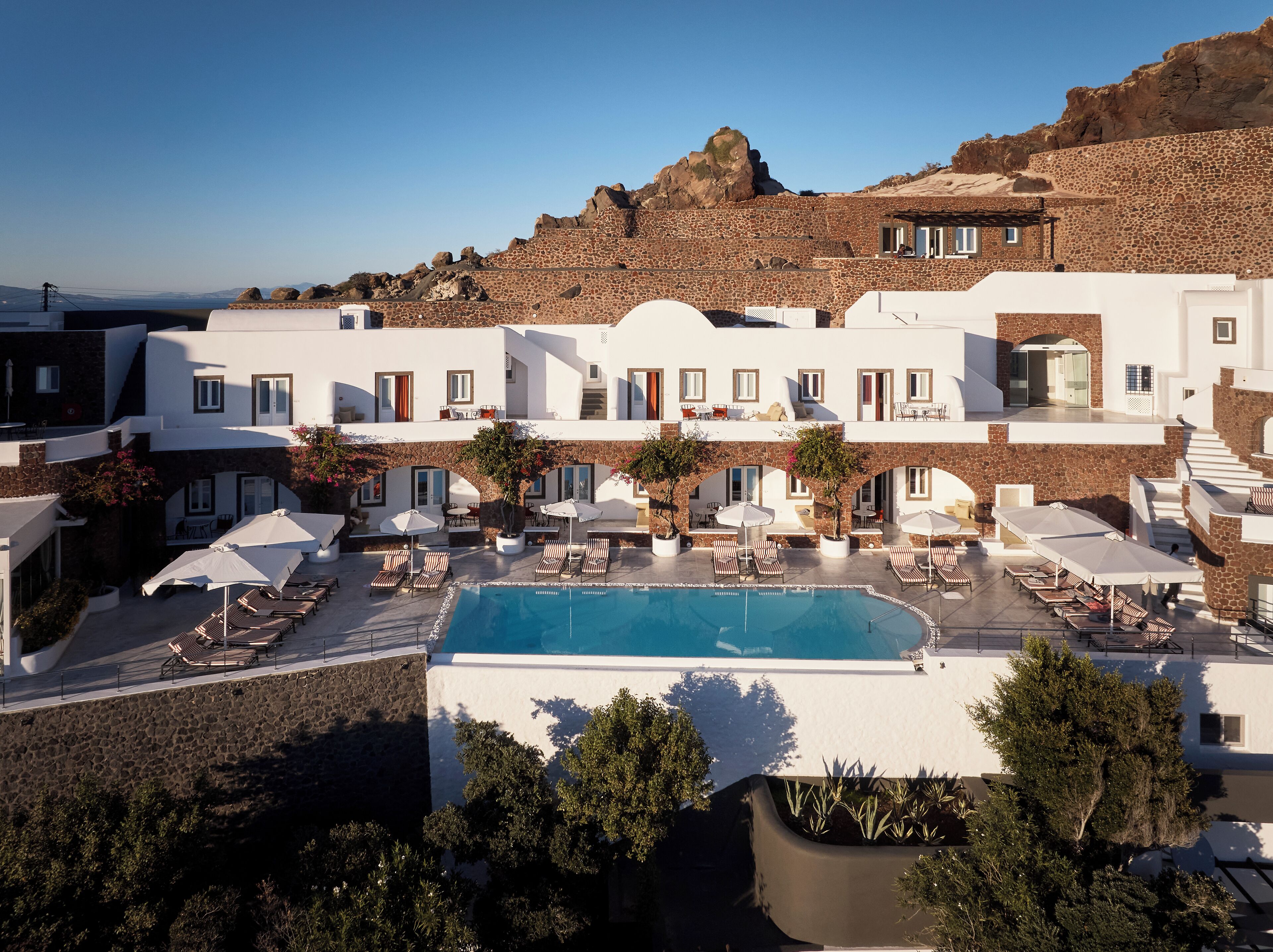 Un hotel con piscina, mobiliario exterior y vistas del paisaje circundante.