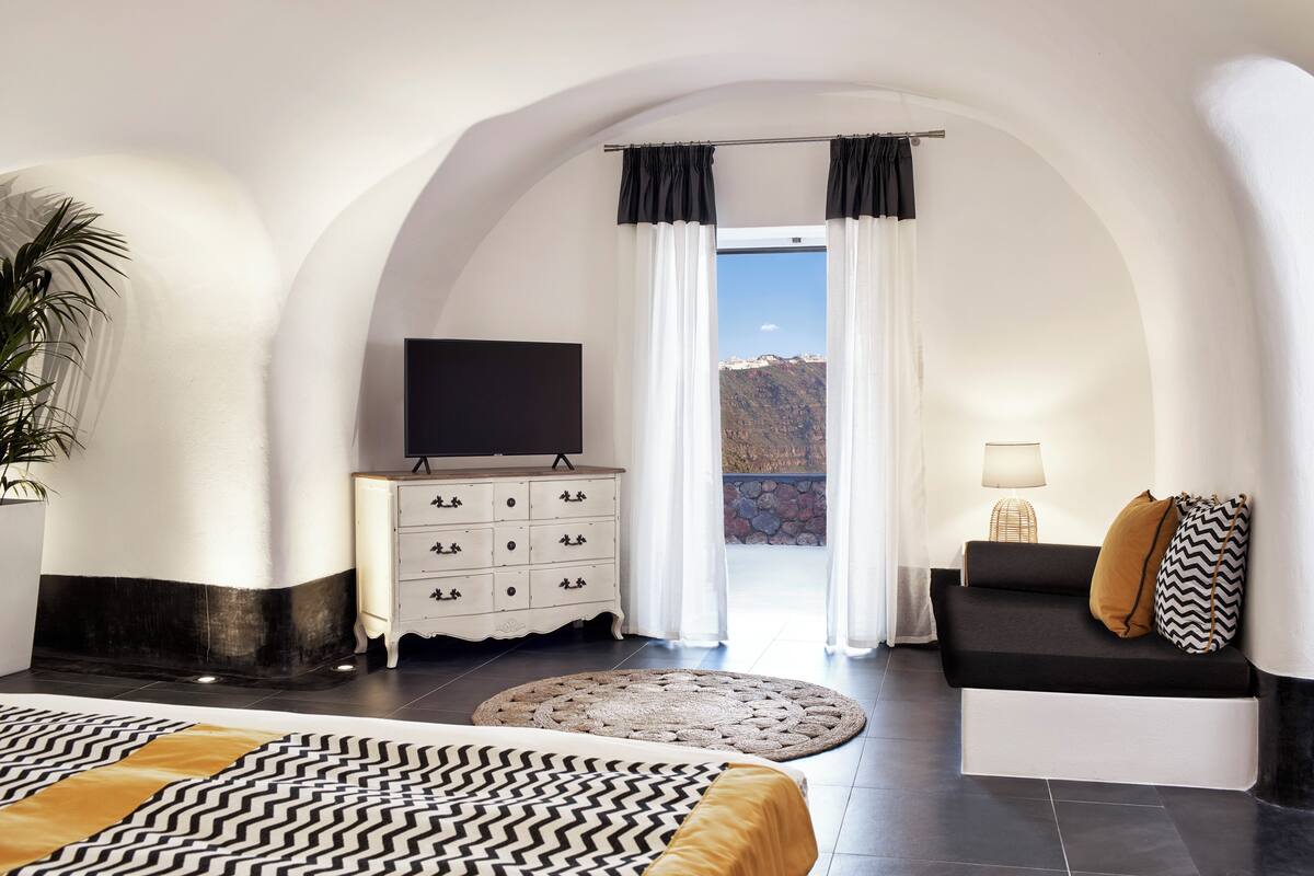 Un dormitorio con cama, sofá, televisor, cómoda y vistas a la montaña.