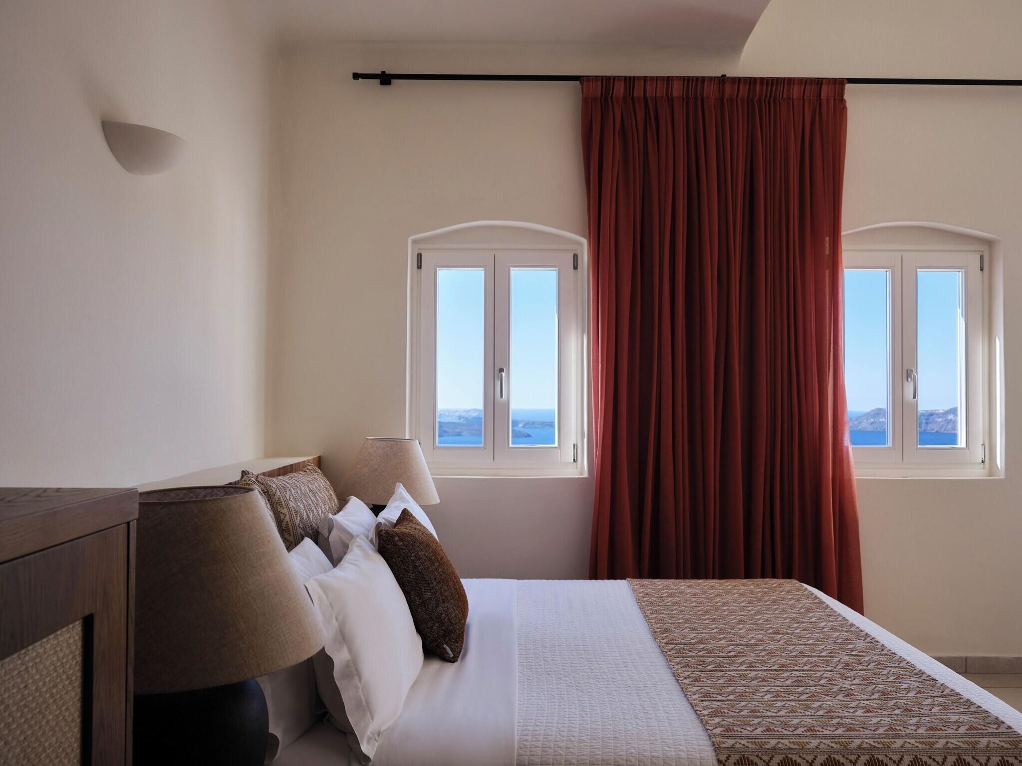 Une chambre à coucher avec un lit, une table de chevet, une lampe et une fenêtre avec des rideaux.