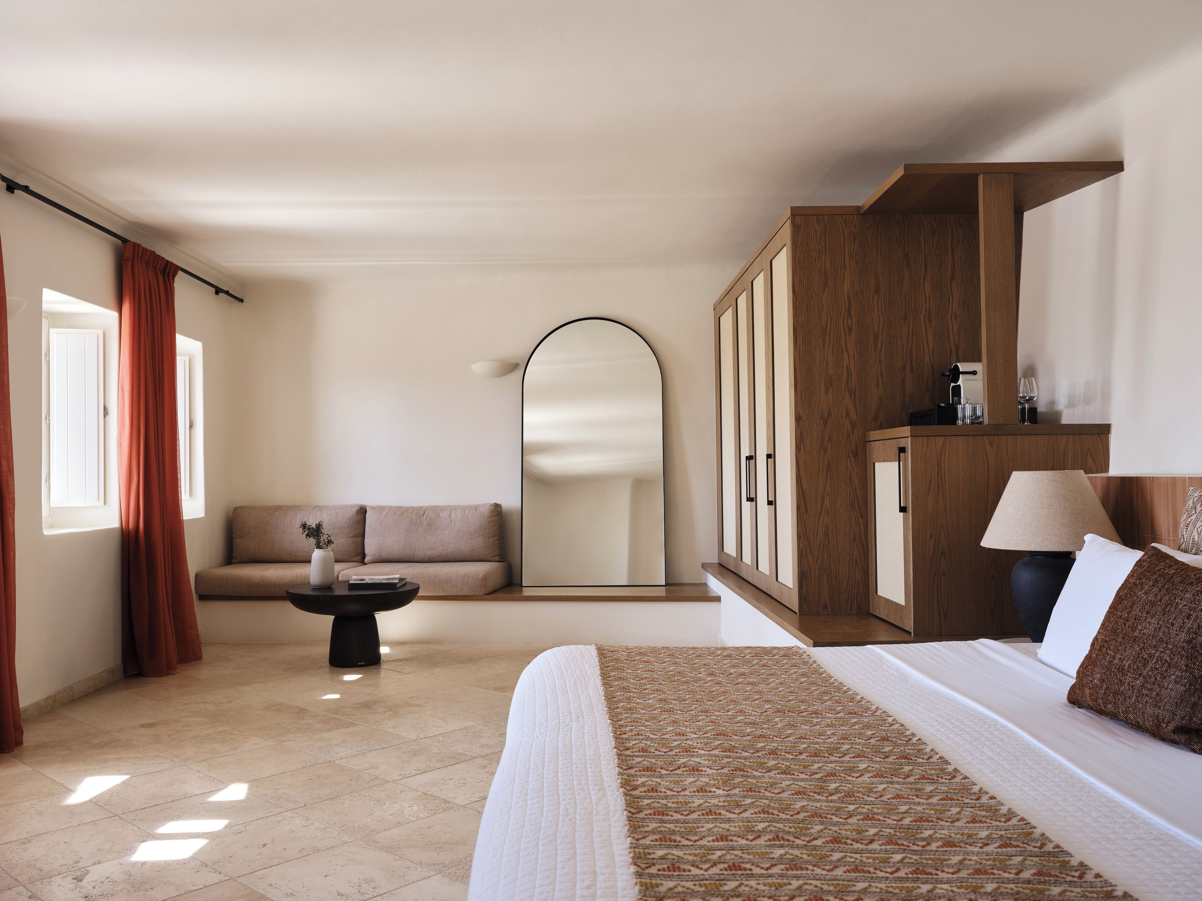 Une chambre d’hôtel avec un lit, un canapé, une petite table, un miroir et une armoire.