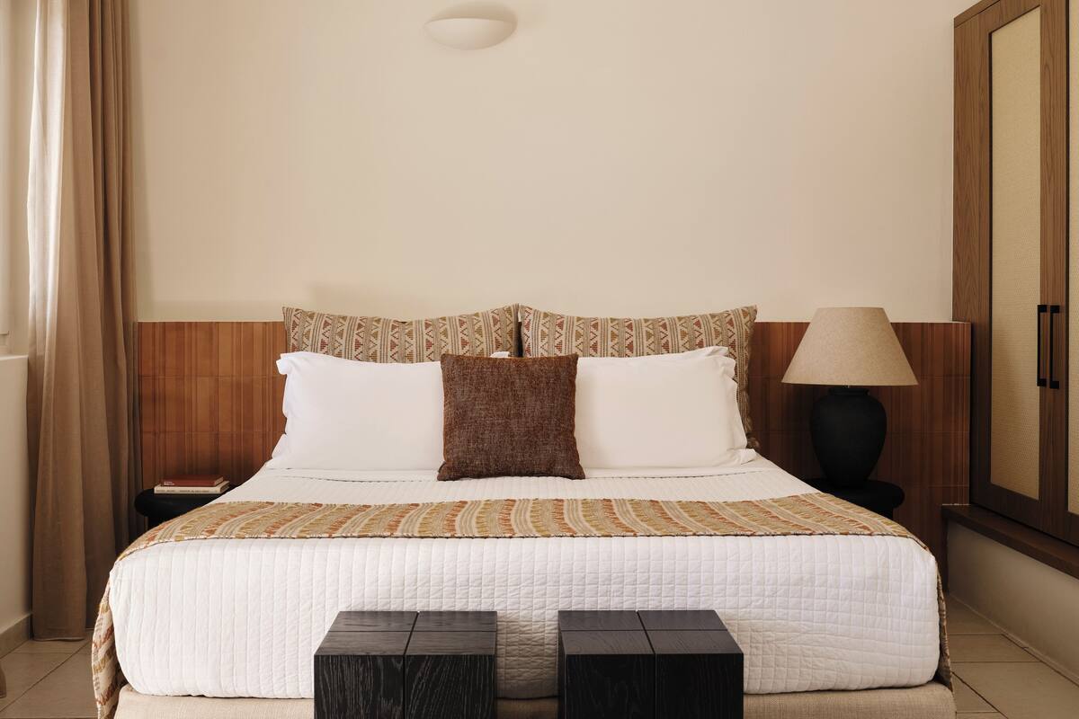 Una habitación de hotel con una cama, una mesita de noche, una lámpara y un armario.