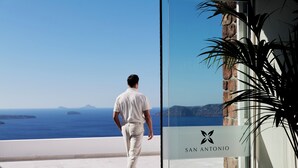 A man walking towards a glass door with a sign reading "SAN ANTONIO". - San Antonio (Santorini)