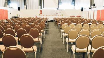 A conference room with rows of chairs facing a stage with a podium and a screen.