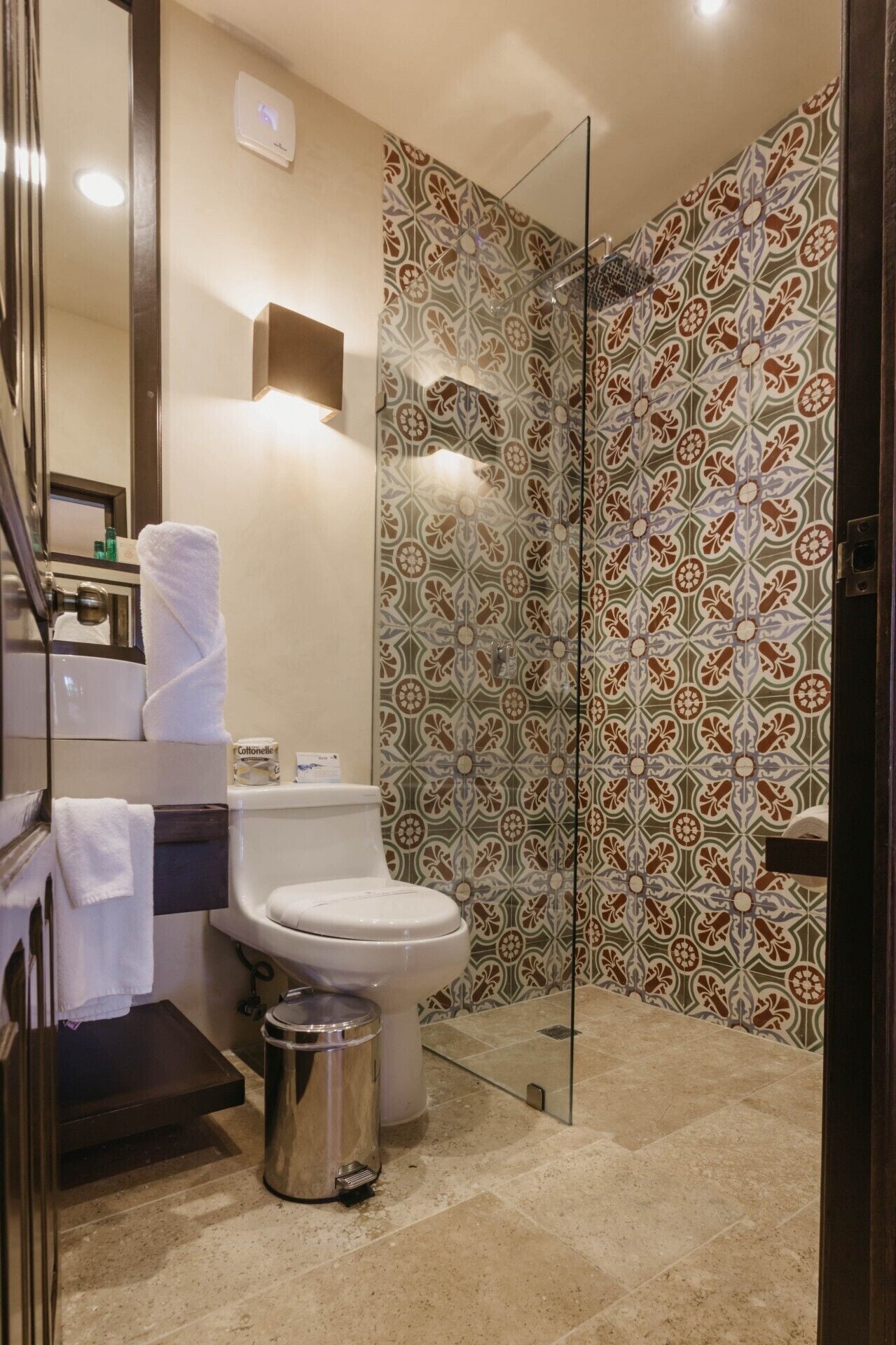 Ein Badezimmer mit Toilette, einer Duschkabine mit Glastür, einem Waschbecken und einem Mülleimer.