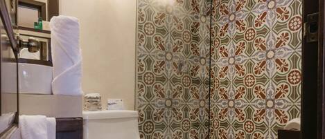Ein Badezimmer mit Toilette, einer Duschkabine mit Glastür, einem Waschbecken und einem Mülleimer.