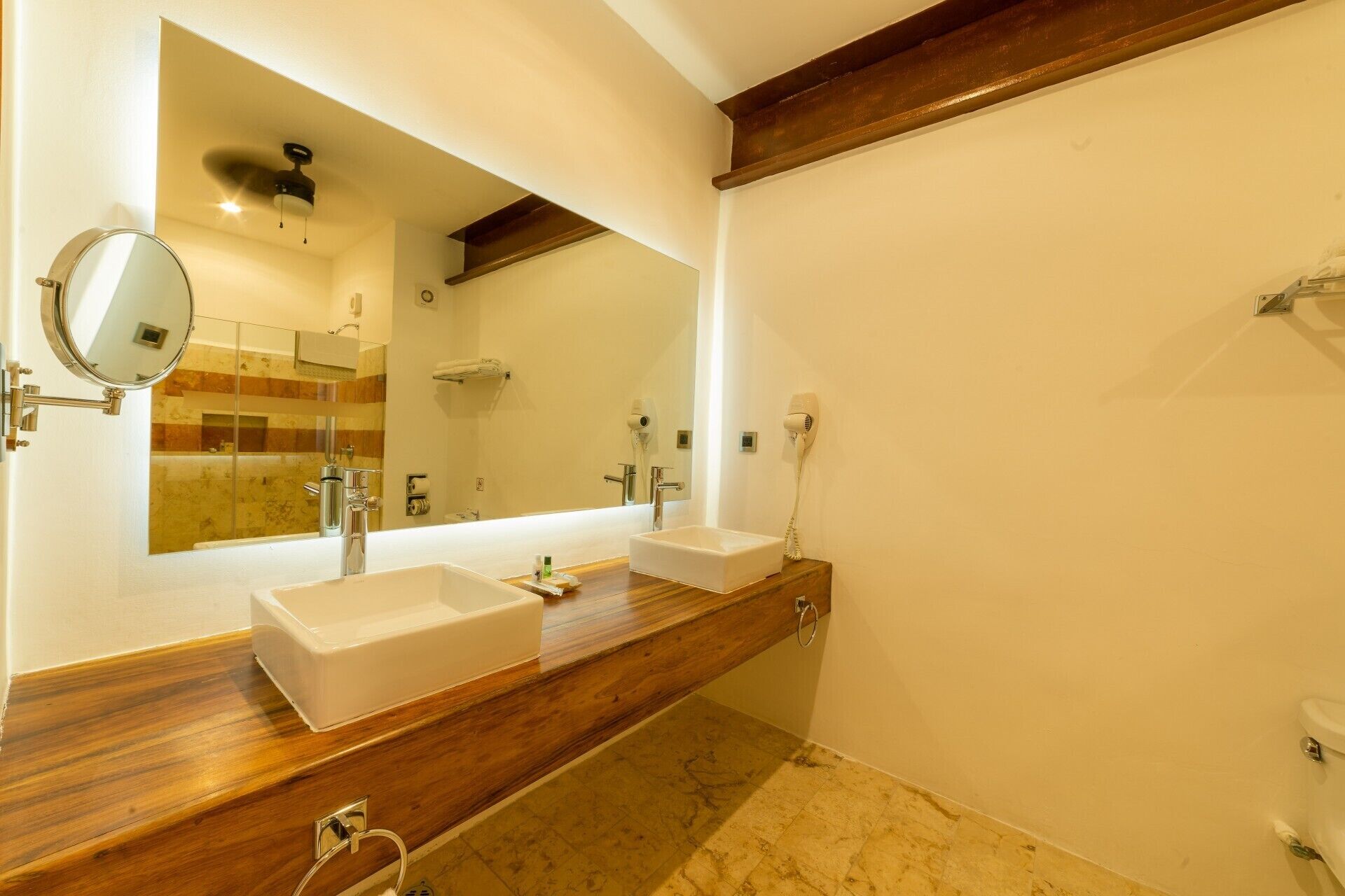 A bathroom with two sinks, a large mirror, and a shower.
