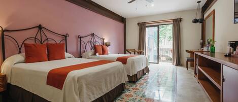 A hotel room with two beds, a ceiling fan, a large window with curtains, a wooden desk, and a tiled floor.