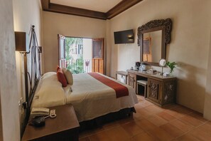 A hotel room with a bed, bedside table, TV, and a mirror. - El Mesón del Marqués (Valladolid)