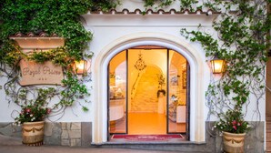 La entrada de Royal Priso, con un amplio arco, plantas en macetas y un cartel.