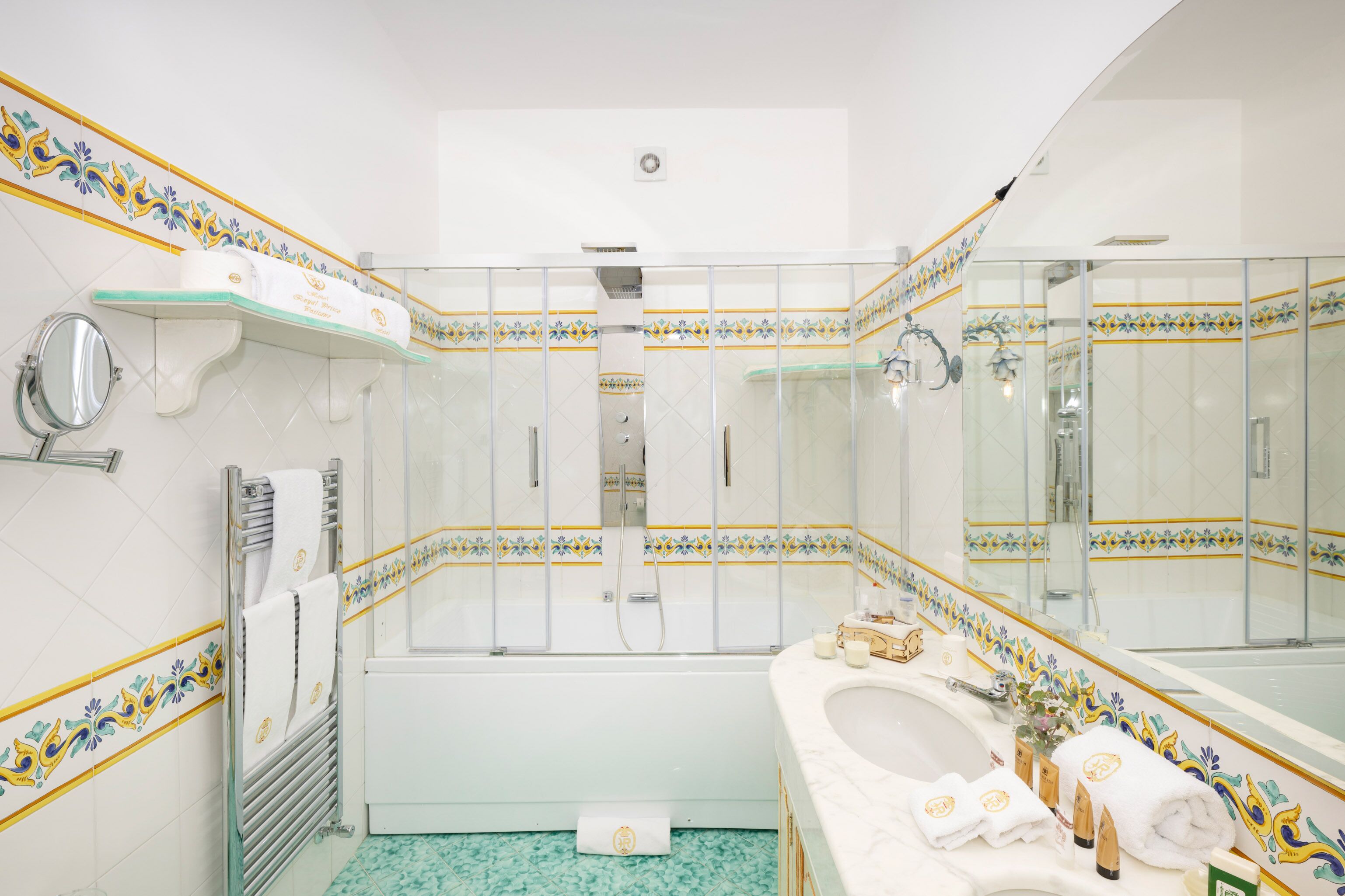 Une salle de bain avec une baignoire, un grand miroir et un lavabo orné de carreaux décoratifs.