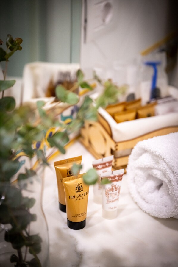 A bathroom with toiletries, a towel, and a plant. - Hotel Royal Prisco (Positano)