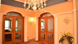 A lobby with two wooden doors labeled 'SALON' and 'RESTAURANT', a marble floor, and a chandelier. - Hotel Miravalle (Naples)