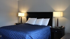 Une chambre d’hôtel avec un grand lit, deux tables de chevet et deux lampes.