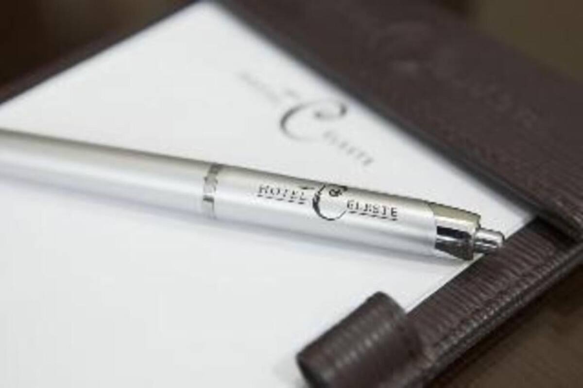 A pen lying on a white card with text, next to a dark brown leather case.