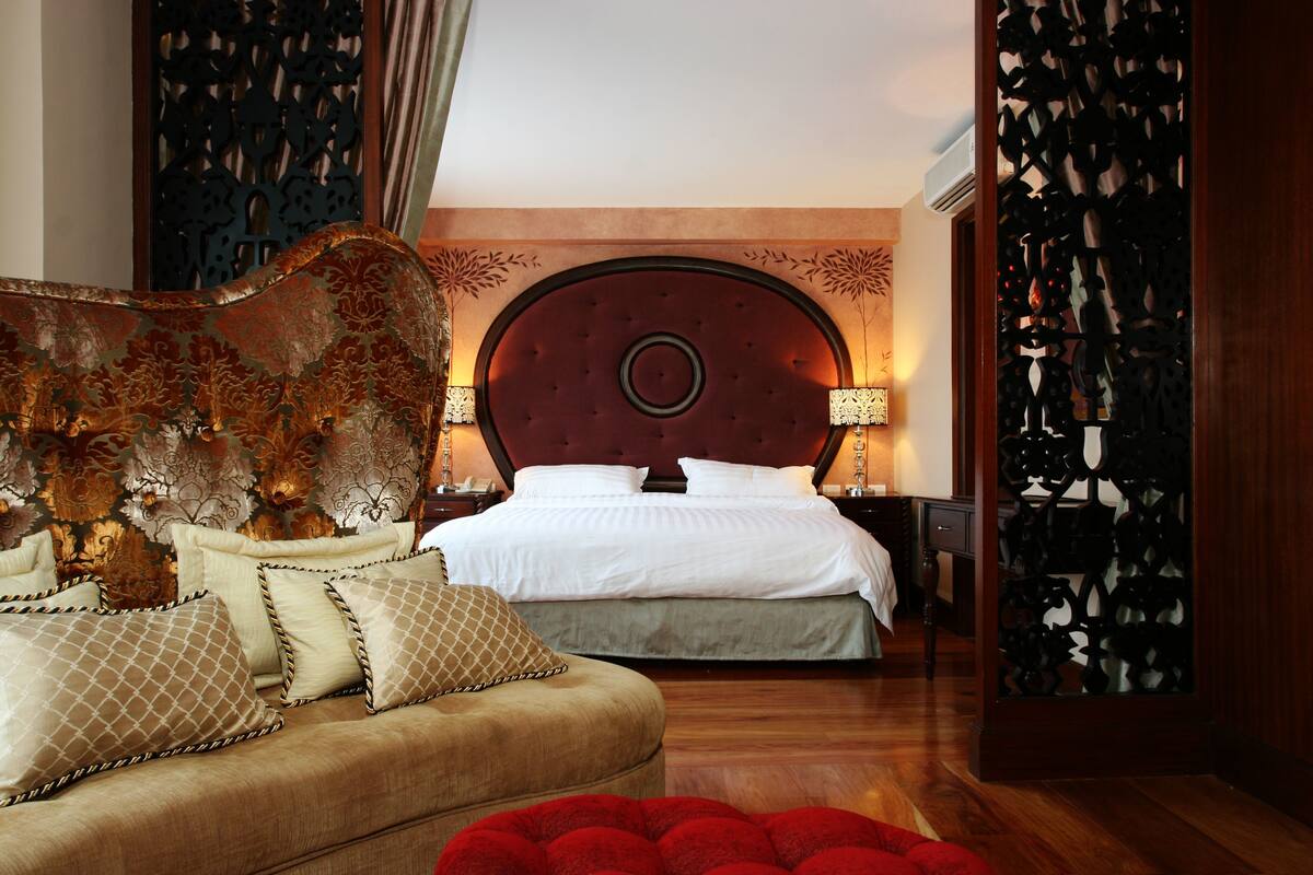 A bedroom with a large bed, a sofa, and a decorative headboard.