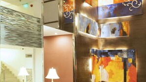 Un hall con un sofá, una lámpara y una pared con arte abstracto.