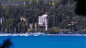 Un bâtiment situé sur la côte, entouré de grands arbres et donnant sur une marina où sont amarrés des bateaux.