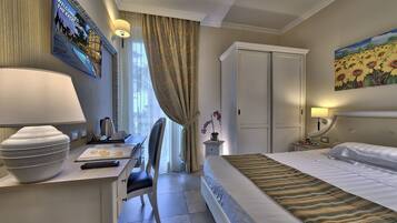 Habitación de hotel con cama, escritorio, silla y un cuadro de girasoles en la pared.