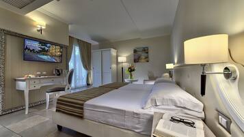 A hotel room with a bed, desk, TV, and a painting on the wall.