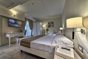Una camera d'albergo con un letto, una scrivania, una TV e un quadro appeso al muro.