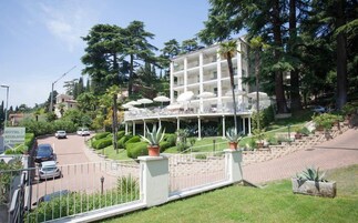Un hotel con terraza, rodeado de follaje y palmeras.