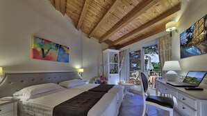 Une chambre avec un grand lit, un bureau avec un ordinateur portable, une chaise et une vue sur l’extérieur.