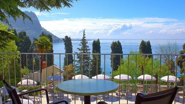 Un espace aménagé au bord de la piscine offrant une vue sur la mer et les montagnes.