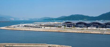 A coastal area with a large, modern building complex by the water, featuring multiple structures with curved roofs.