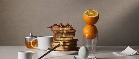 A breakfast setup with toast, orange slices, and a cup of tea on a table.