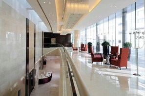 A modern hotel lobby with a glass railing, seating area, and a reception desk. - Hong Kong SkyCity Marriott Hotel (Chek Lap Kok)