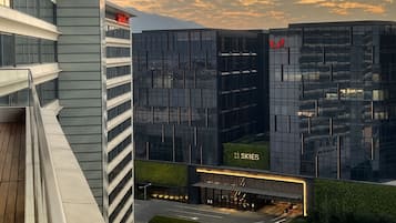 Un edificio moderno con fachada de vidrio, un cartel que dice "11 Skies" y un jardín en la azotea.