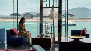 Un salon moderne avec vue sur la mer, comprenant un canapé, une table basse et une étagère décorative.