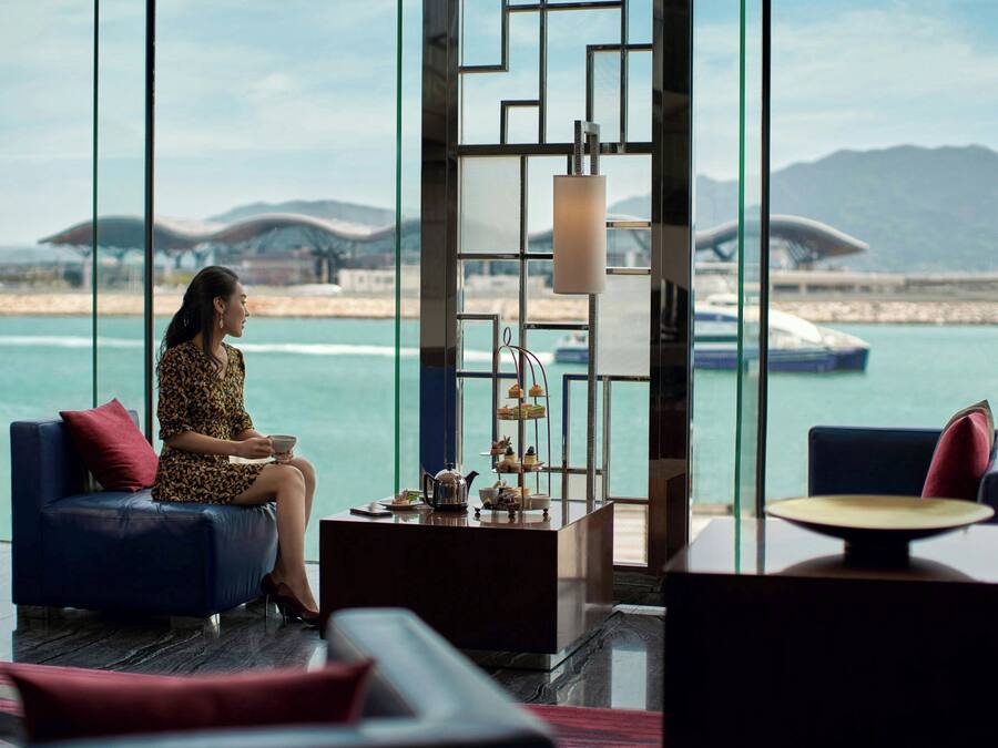 A modern lounge with a view of the sea, featuring a sofa, a coffee table, and a decorative shelf.
