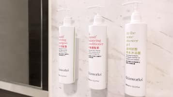 Three bottles of thisworks shampoo, conditioner, and shower gel on a marble surface.