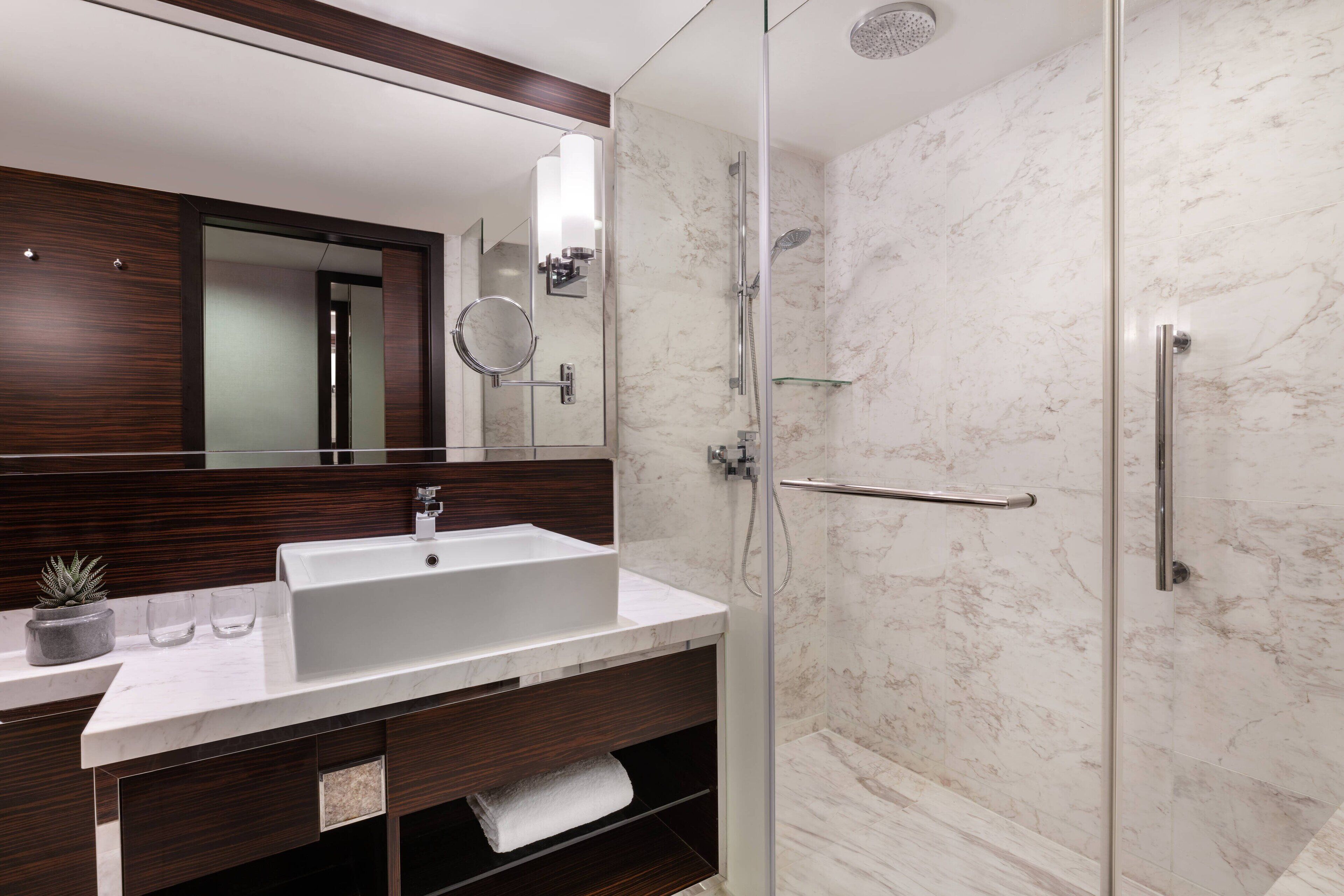 Un baño moderno con un espejo grande, un lavabo y una ducha.