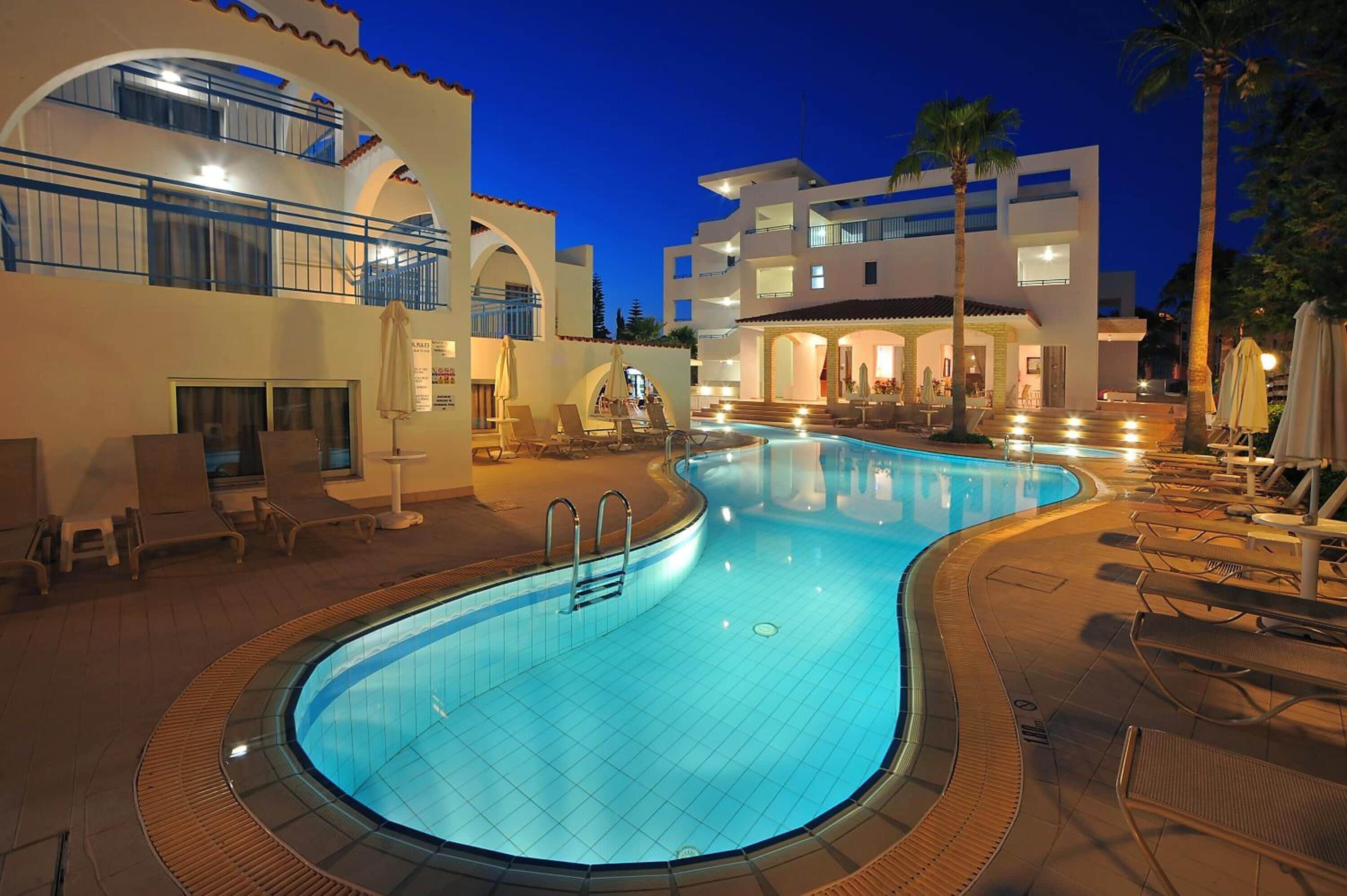 A swimming pool with lounge chairs, a staircase leading to a building, and palm trees.