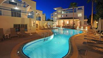 A swimming pool with lounge chairs, a staircase leading to a building, and palm trees.