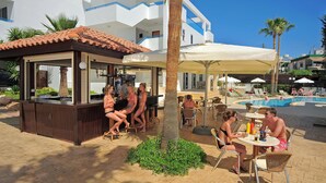 A poolside area with a bar, outdoor seating, and a pool. - Petrosana Hotel Apartments (Ayia Napa)