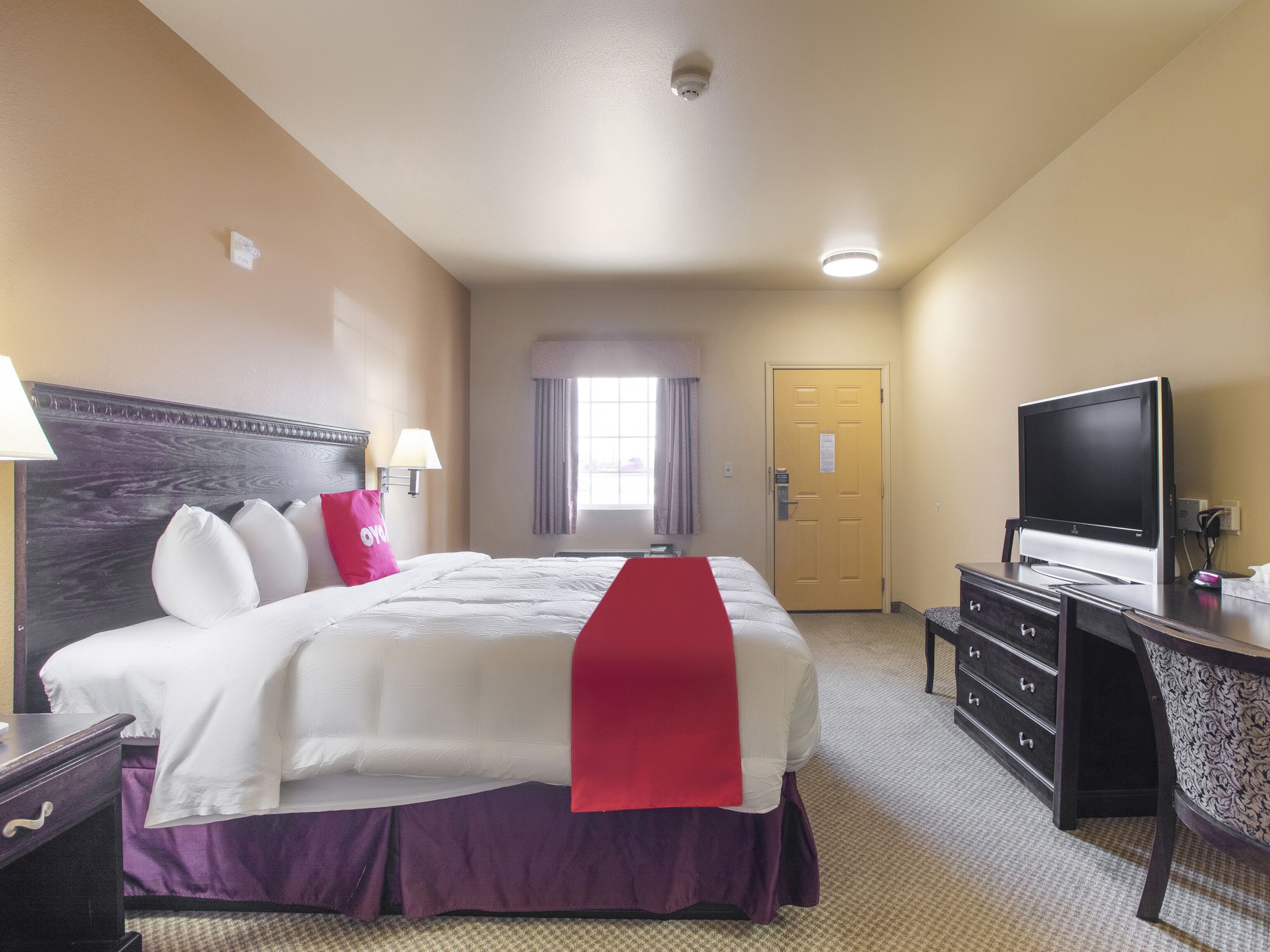 Une chambre d’hôtel avec un grand lit, une télévision, un bureau et une porte.