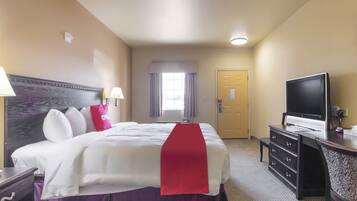 Une chambre d’hôtel avec un grand lit, une télévision, un bureau et une porte.