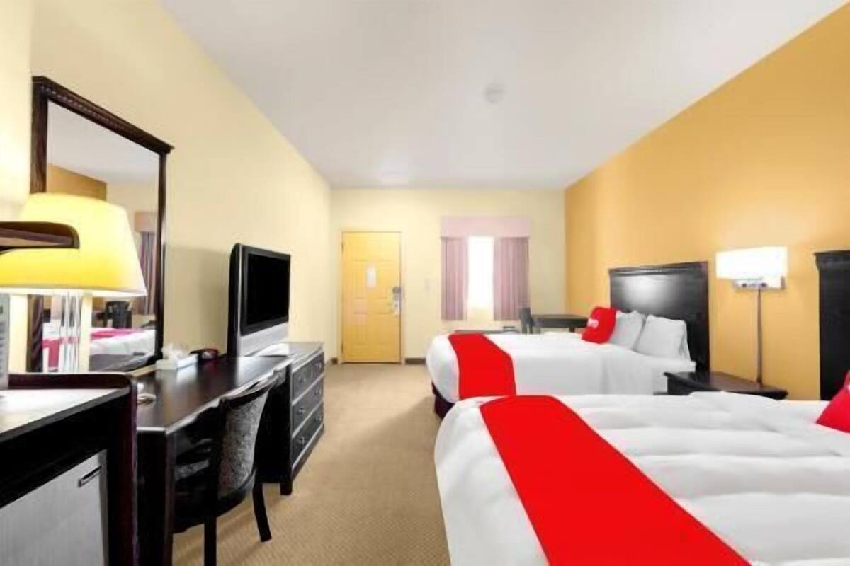 Una habitación de hotel con dos camas, un escritorio, un televisor y una lámpara.