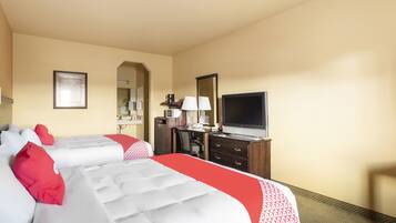 A hotel room with two beds, a desk, a television, and a mirror.