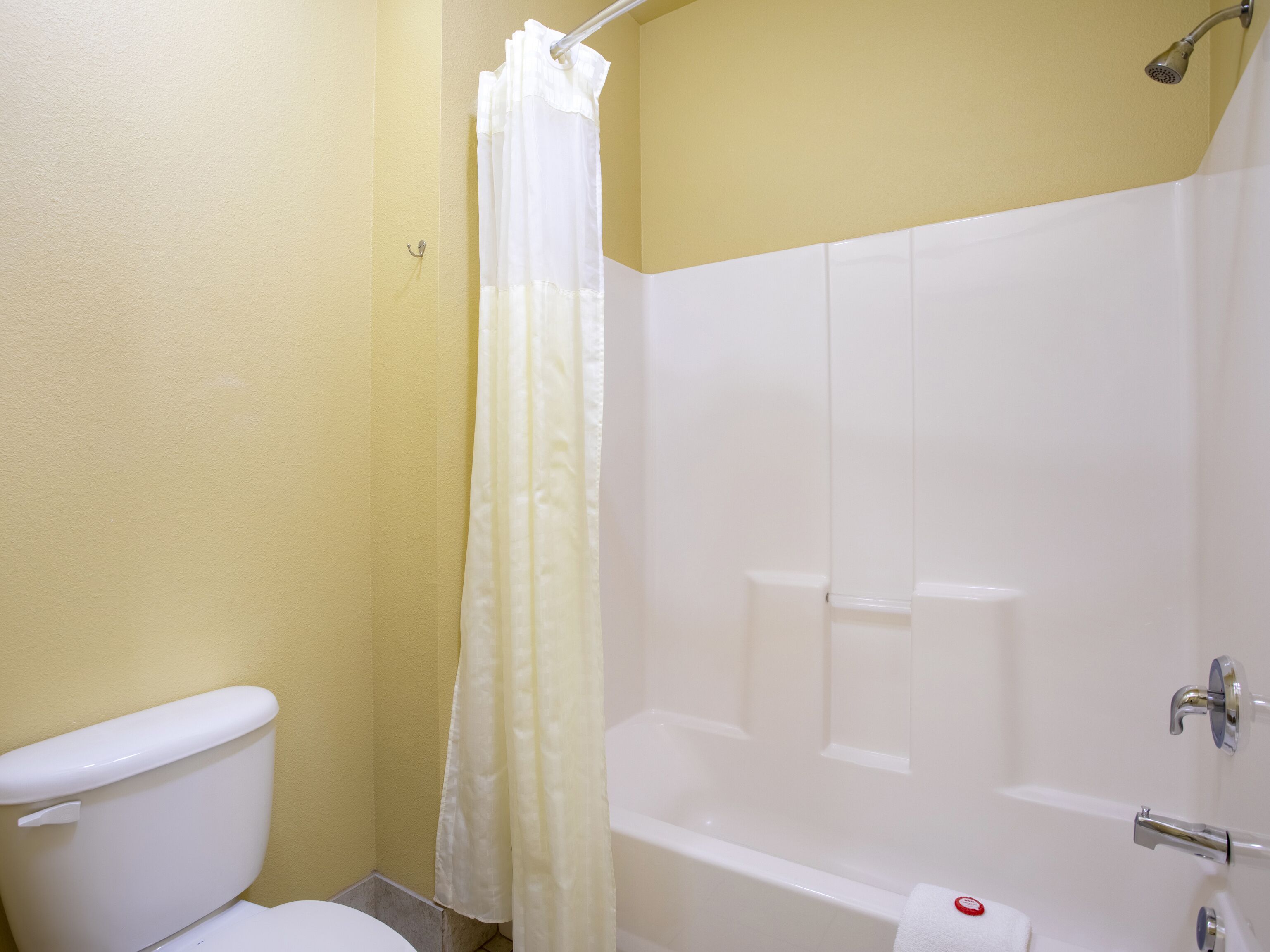 A bathroom with a toilet, a bathtub, and a shower curtain.