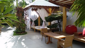 A covered outdoor seating area with tables and chairs, surrounded by plants and a small garden. - Boracay Beach Club (Boracay Island)