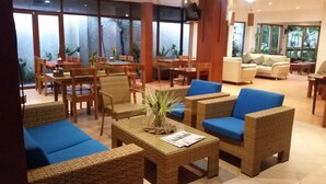 A spacious lobby with wicker furniture, a coffee table with a newspaper, and large windows offering a view of the outdoors. - Boracay Beach Club (Boracay Island)
