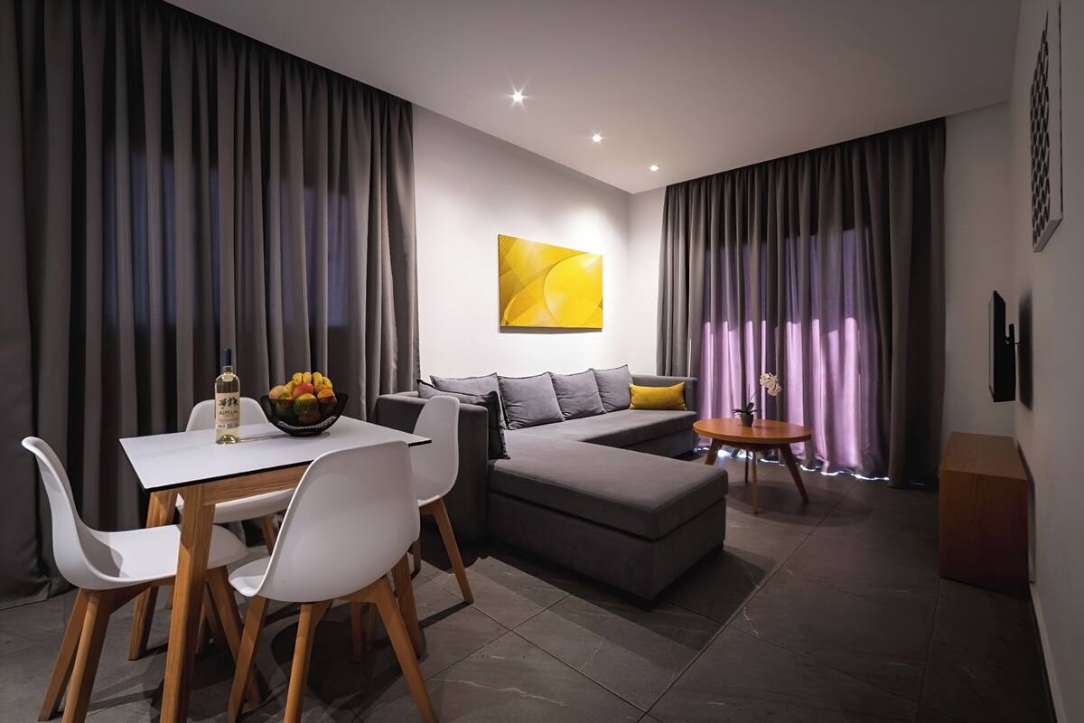 A modern living room with a sofa, dining table, and chairs.