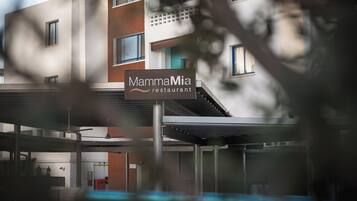 A restaurant named "MammaMia" with a modern architectural design, featuring a covered outdoor seating area and multiple windows.