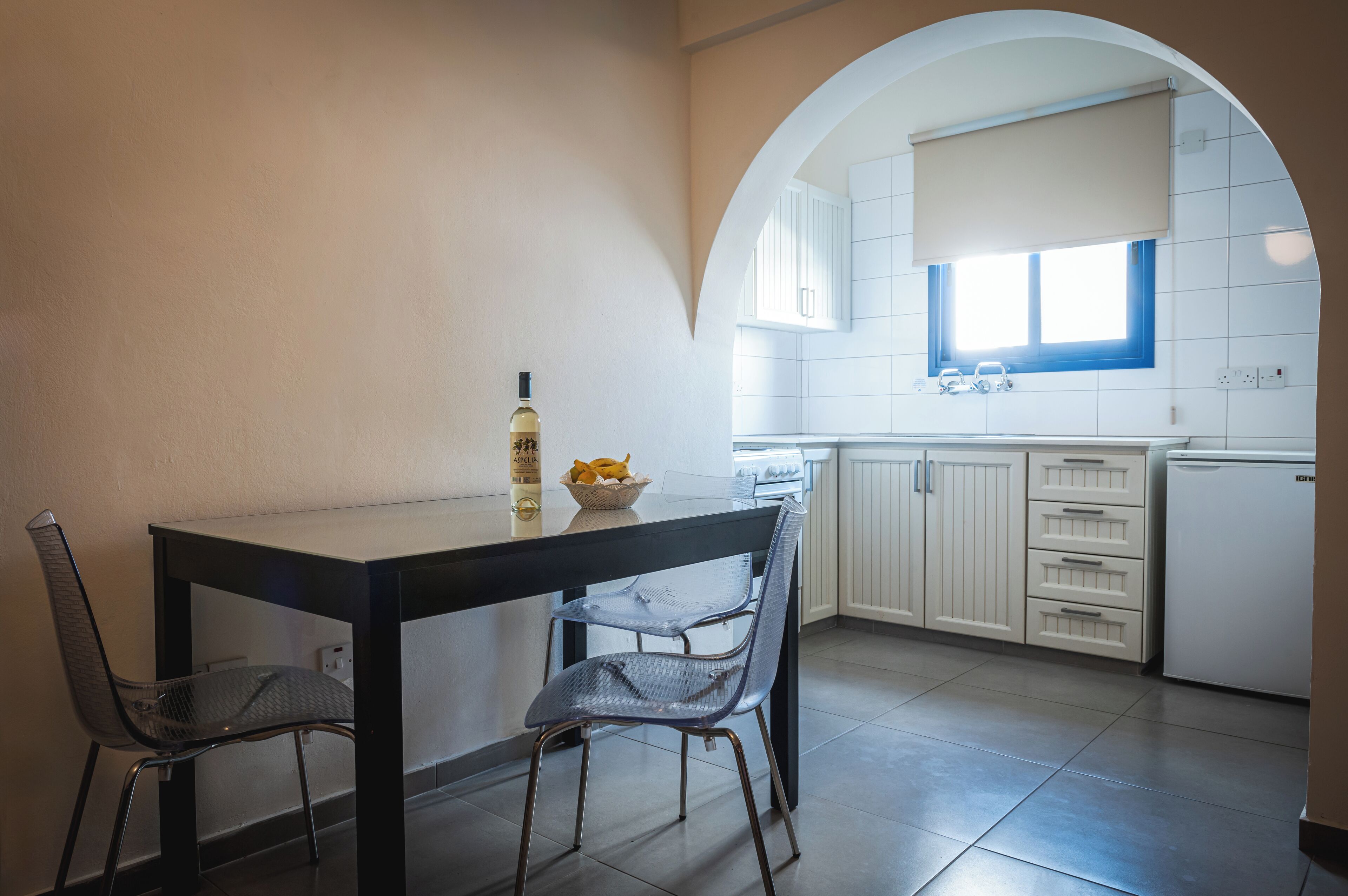 Une cuisine moderne avec des meubles blancs, une table à manger noire et deux chaises.
